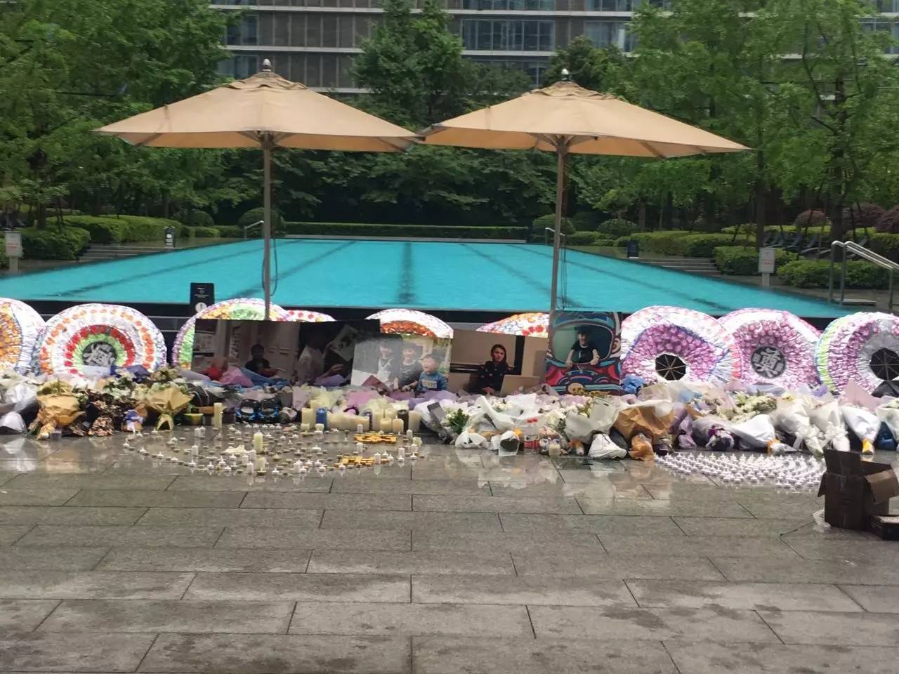 火災后，小區(qū)業(yè)主自發(fā)組織悼唁活動，草坪上逝者照片前擺滿了花圈、花束、蠟燭。（新京報記者王婧祎攝）
