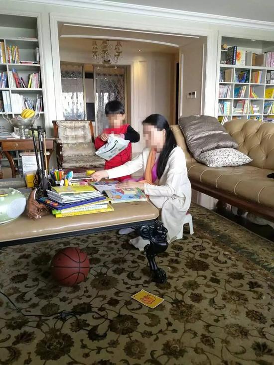 朱小貞和小兒子在客廳里，背后書架為起火點。（受訪者供圖）